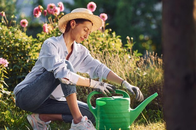 Avec de l'eau verte peut Jeune femme joyeuse est dans le jardin pendant la journée