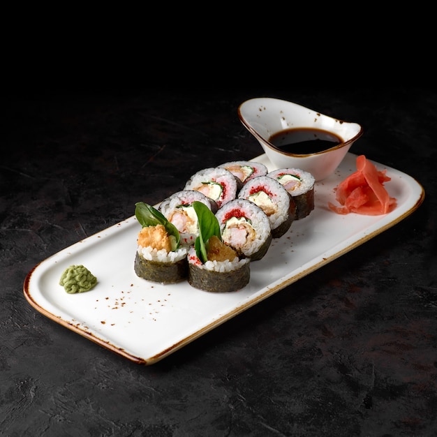 Ebi Tempura Roll avec crevette, concombre et crème au fromage placé sur un fond texturé noir