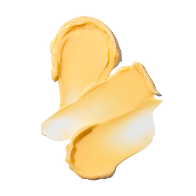 Photo Échantillon de cosmétiques à texture crème jaune pour le visage et le corps sur un fond isolé