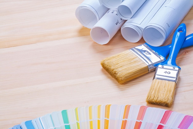 Photo Échantillonneur de couleurs de plans blancs et deux pinceaux avec poignées bleues sur planche de bois avec version horizontale copysapce