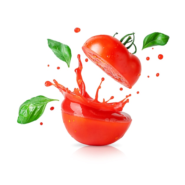 Éclabousser le jus de tomate avec des feuilles de basilic volant isolé sur fond blanc.