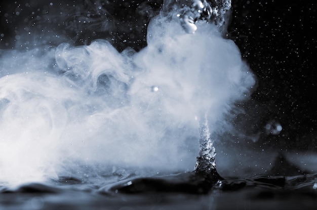 Photo Éclaboussure d'eau bouillante avec de la vapeur sur fond noir libre