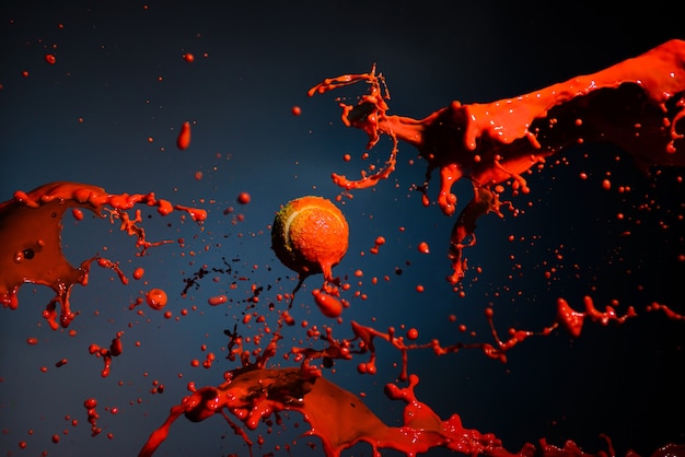 Éclaboussure de peinture rouge et balle de tennis