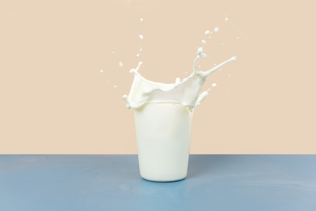 Les éclaboussures de lait dans la tasse sont sur un fond jaune et gris