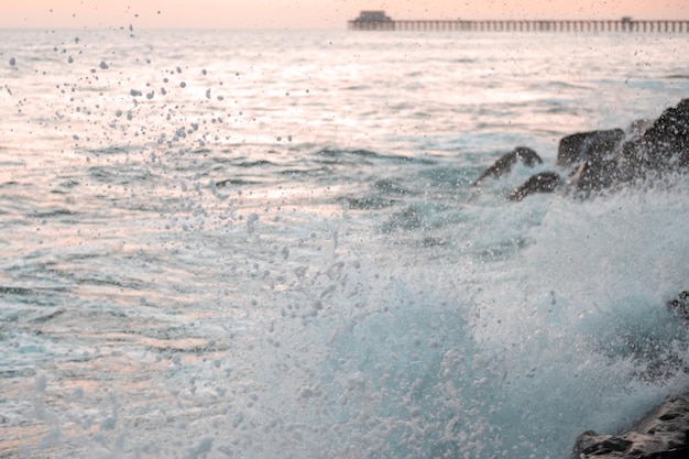 Des éclaboussures de vagues de l'océan s'écrasent contre des rochers au coucher du soleil États-Unis Californie