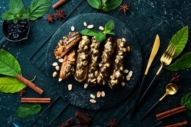 Eclair à la crème de cacahuètes au chocolat Dessert au chocolat et aux noix sur une plaque en pierre noire Vue de dessus Style rustique