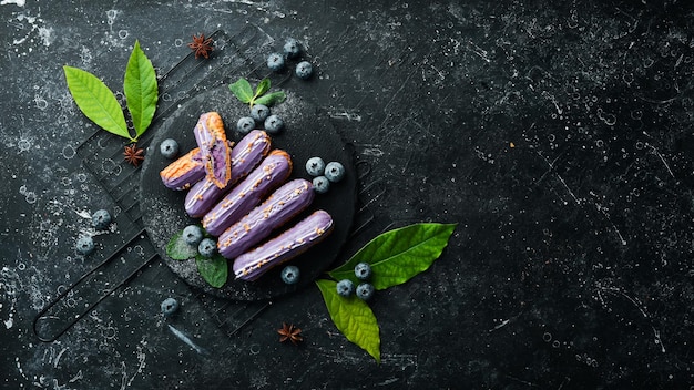 Eclair à la crème de myrtille Dessert aux myrtilles sur une assiette en pierre noire Vue de dessus Style rustique