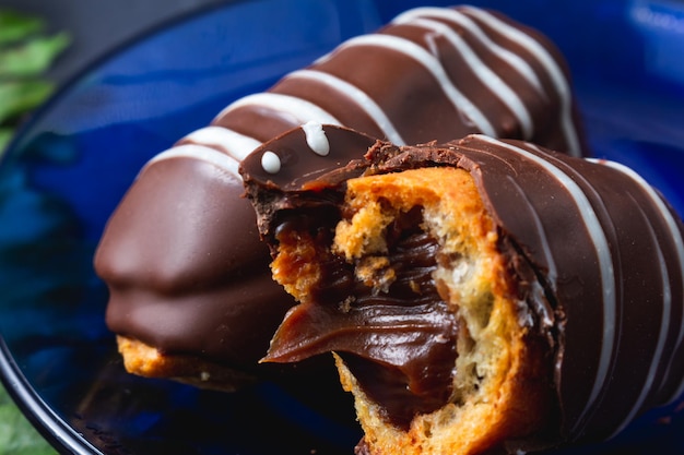 Eclair avec garniture au chocolat sur table en bois.