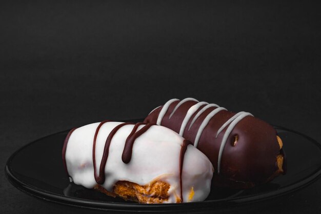 Eclairs fourrés au chocolat et chocolat blanc sur une surface noire.