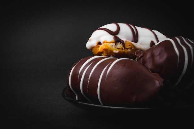 Eclairs fourrés au chocolat et chocolat blanc sur une surface noire.