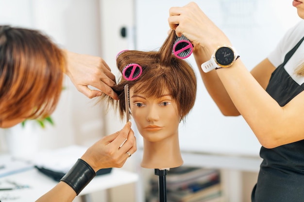 Photo École de coiffure - étudiante adulte s'entraînant à se coiffer avec un rouleau à cheveux