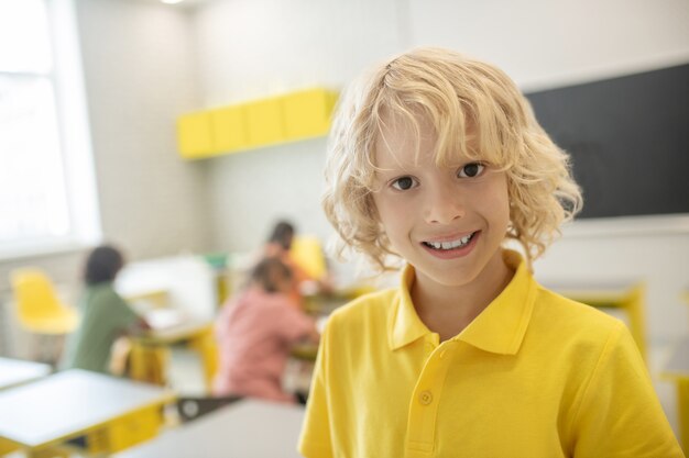 À l'école. Écolier mignon en tshirt jaune souriant bien