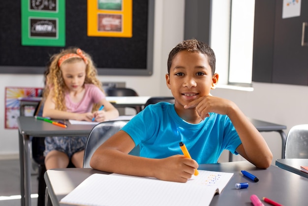 À l'école, dans la salle de classe, un garçon biracial et deux filles blanches se concentrent sur leur travail.