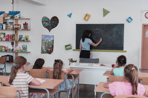 L'école primaire L'enseignante aide l'élève en écrivant la réponse sur le tableau.