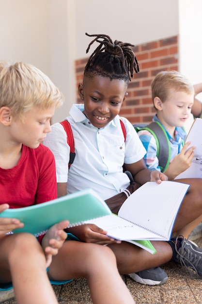 Un écolier afro-américain souriant étudie avec un camarade de classe caucasien à l'école.