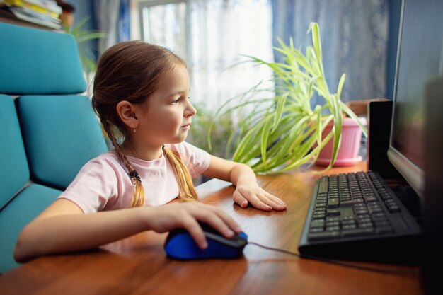 Photo Écolier assis à la maison et jouer à l'ordinateur
