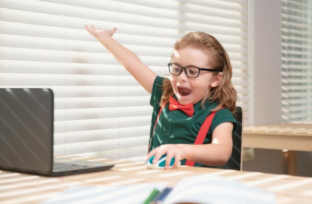 Photo un écolier caucasien a un appel vidéo en classe distante avec un professeur utilisant un ordinateur portable un petit enfant heureux agite