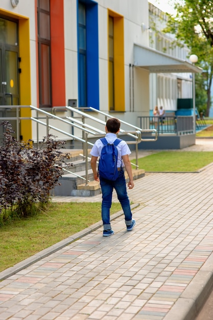écolier en chemise blanche et sac à dos bleu va à l'école