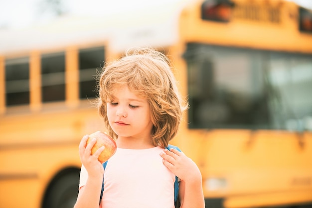 Photo Écolier dans le bus scolaire. élève d'enfant d'école avec la pomme.