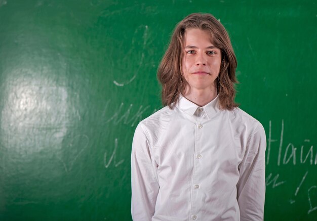 Photo Écolier dans une chemise blanche répondant au tableau noir dans la salle de classe