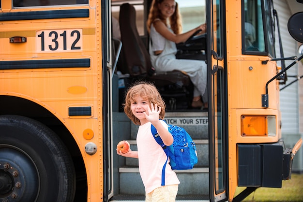 Photo Écolier devant le bus scolaire avec pomme et sac