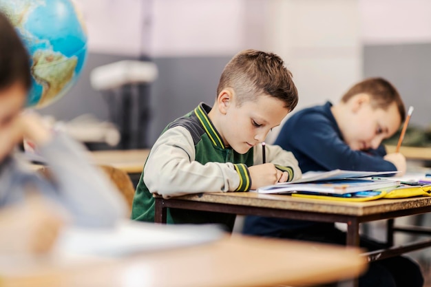 Un écolier écrivant ses devoirs en classe