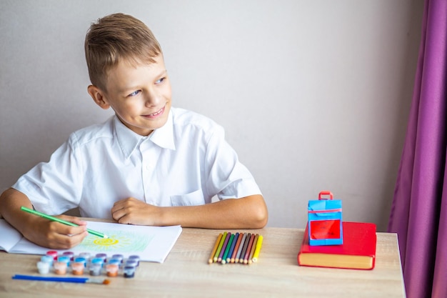 un écolier est assis à un bureau sur fond de manuels scolaires avec un panneau jaune de retour à l'école