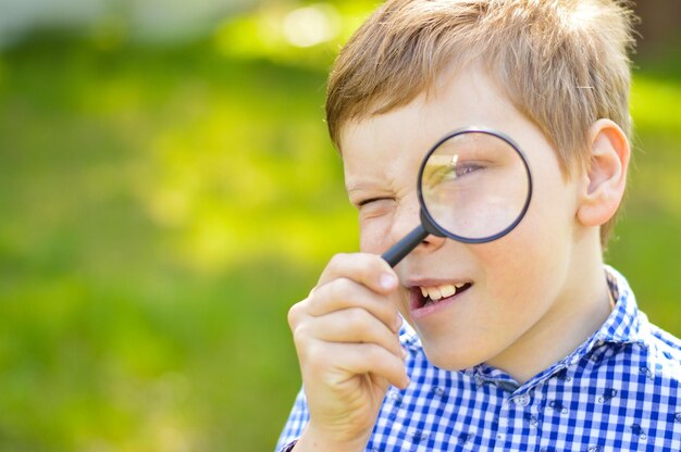 Un écolier explore la nature avec une loupe Vacances d'été pour les enfants curieux dans la forêt Randonnée Futur scientifique botaniste