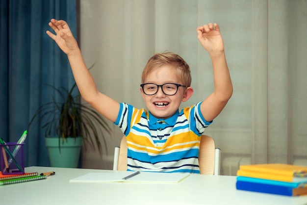 L'écolier fait ses devoirs assis à table à la maison