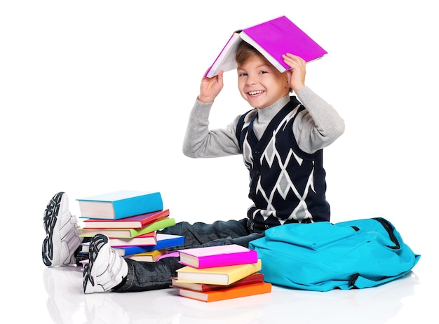 Un écolier heureux assis sur le sol avec un sac à dos et des livres isolés sur un fond blanc