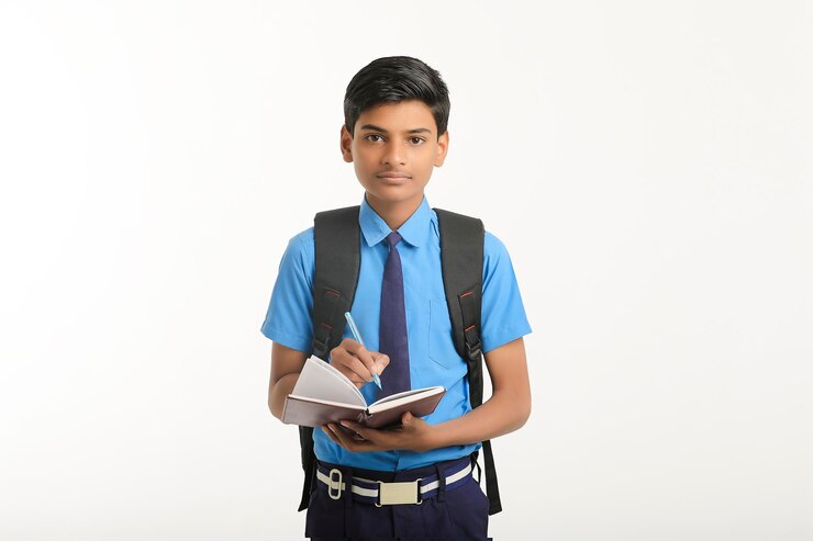 Écolier indien en uniforme et tenant un journal à la main sur fond blanc