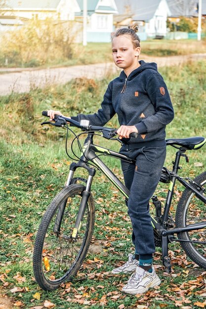 Un écolier junior blond en tenue décontractée aime faire du vélo dans la campagne