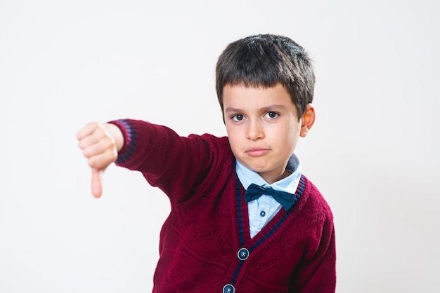 L'écolier en pull montre un pouce vers le bas avec une expression faciale négative