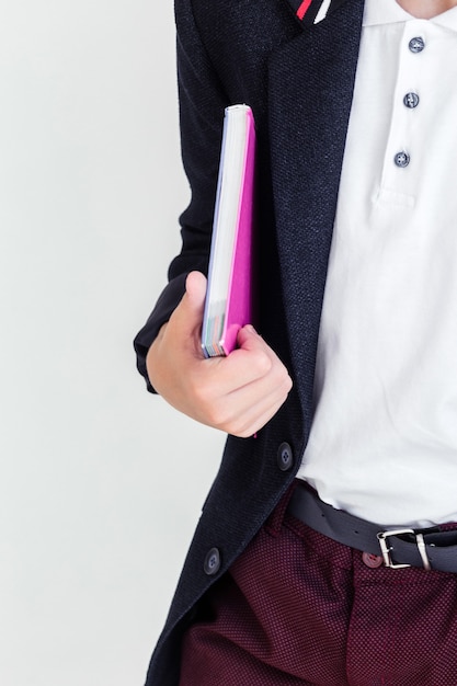 Un écolier se tient sur un fond blanc dans un pantalon d'uniforme scolaire une veste et une chemise un garçon ho...