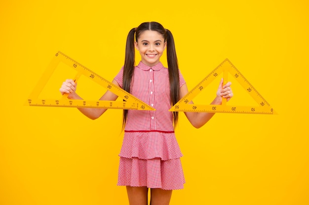 Une écolière adolescente étudie les mathématiques ou la géométrie leçon mesurer la taille Règle mathématique pour mesurer Bonne écolière positive et souriante