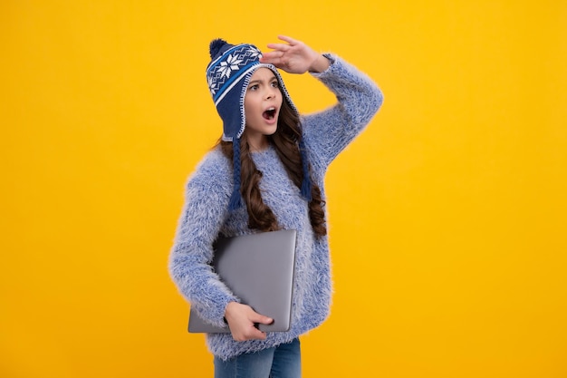 Écolière adolescente excitée Vacances scolaires d'automne Retour à l'école Écolière adolescente en vêtements d'automne tenir un ordinateur portable sur fond de studio isolé jaune