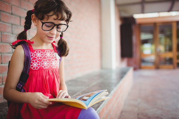 Écolière assise lisant un livre