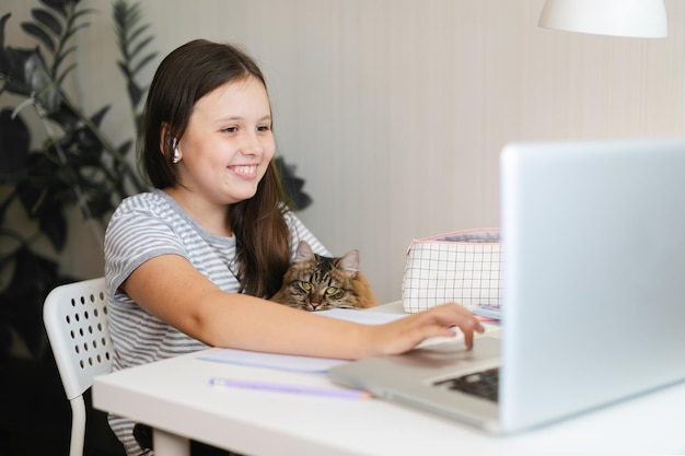 Photo une écolière en classe avec un animal de compagnie une fille qui fait ses devoirs avec un ordinateur portable à la maison