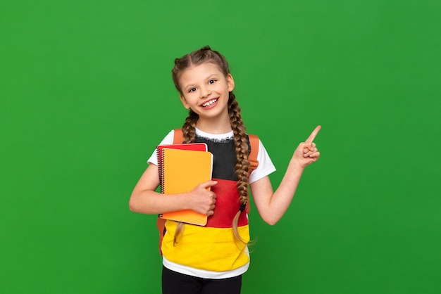 Une écolière avec un drapeau allemand sur son t-shirt pointe vers le côté à une publicité sur un fond vert isolé L'éducation à l'étranger