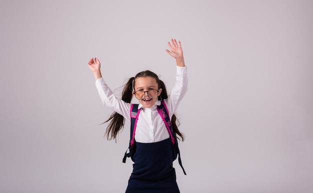 Une écolière drôle en uniforme avec des lunettes s'amuse sur un fond blanc avec une place pour le texte