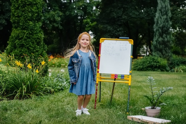 Une écolière écrit des leçons sur un tableau noir et est engagée dans une formation en plein air