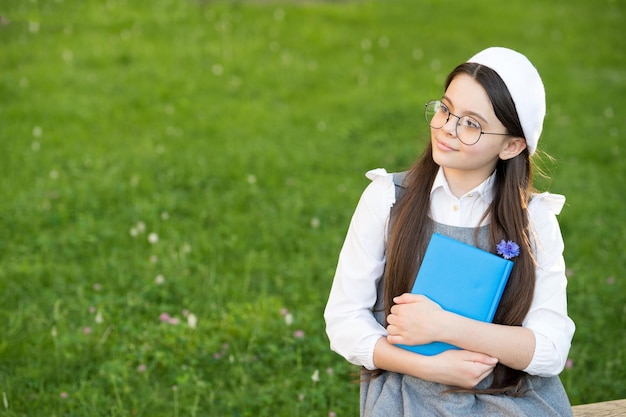 Écolière élégante enfant fille lisant un livre dans le concept d'écrivain de poésie du parc