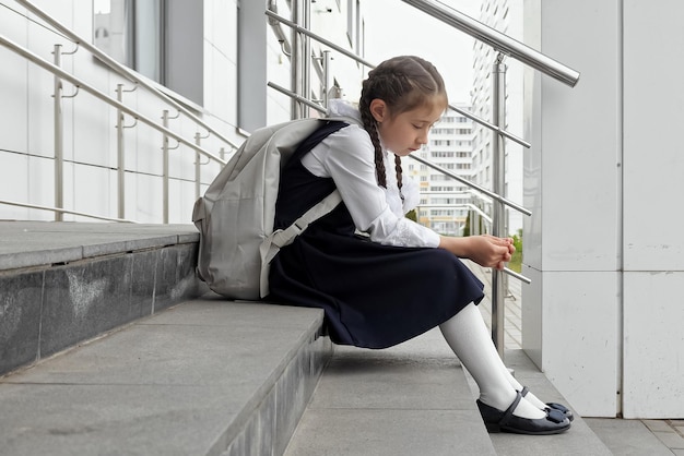 Une écolière est assise dans les escaliers sans vouloir aller à l'école