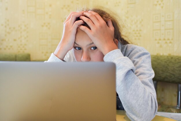 écolière faisant ses devoirs à l'ordinateur apprentissage en ligne devoirs ennuyeux à distance