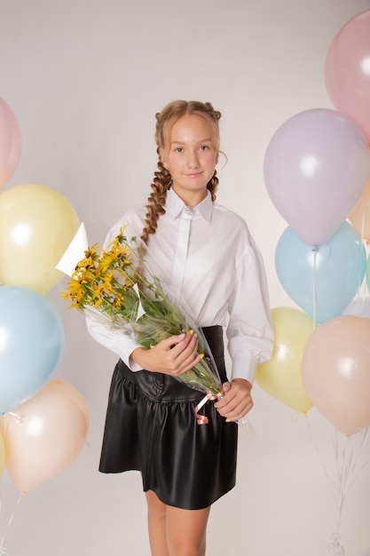 Écolière fille, lycéenne avec des fleurs et des boules sur fond blanc