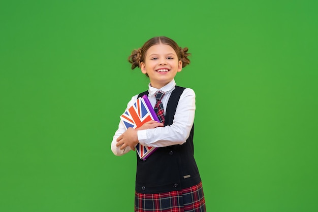 Une écolière joyeuse tient un manuel d'anglais dans ses mains. l'apprentissage des langues étrangères à l'école. un étudiant joyeux avec un livre sur un fond isolé.. copiez l'espace.