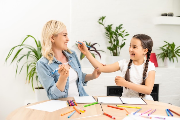 écolière et mère faisant ensemble leurs devoirs à la maison.