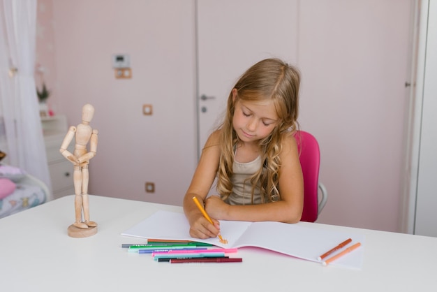 Une écolière mignonne, une enfant de sept ans, est engagée dans l'apprentissage à distance, des leçons de dessin, des devoirs à la maison.