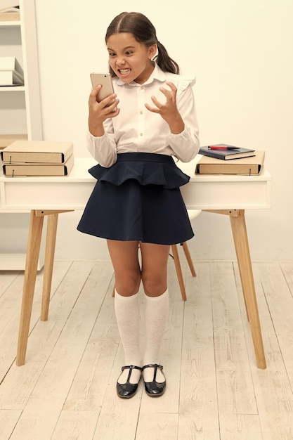 écolière avec téléphone dans la salle de classe colère écolier avec téléphone au bureau écolier fille avec téléphone photo d'écolier avec phone