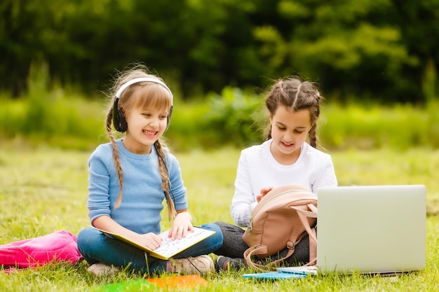 Des écolières assez élégantes étudient une leçon en ligne dans la cour, la distance sociale pendant la quarantaine, l'auto-isolement, le concept d'éducation en ligne